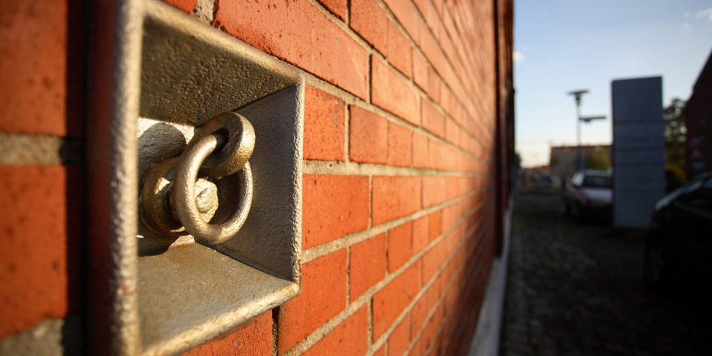 Im Vordergrund ist eine rote Steinmauer mit einer Ausbuchtung.