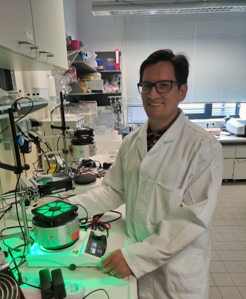 A man with glasses and a white coat stands in a laboratory.