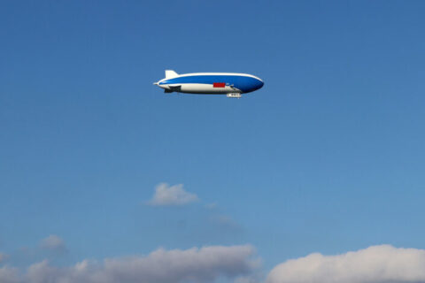 A flying zeppelin against a blue sky.