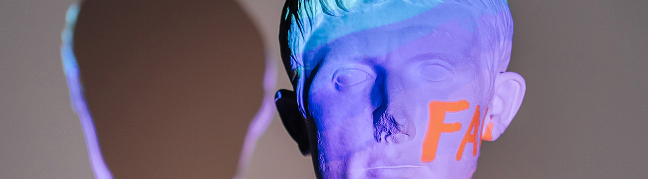 A head bust illuminated with blue and purple light, with the letters F and U in orange.