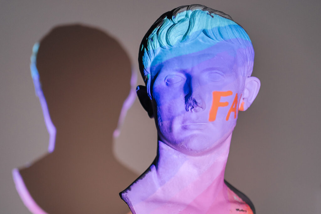 A head bust illuminated with blue and purple light, with the letters F and U in orange.