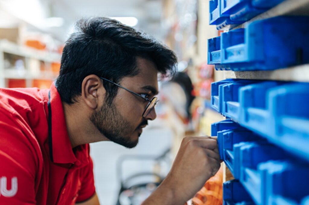 A man wearing a red tshirt while looking into a blue shelf.