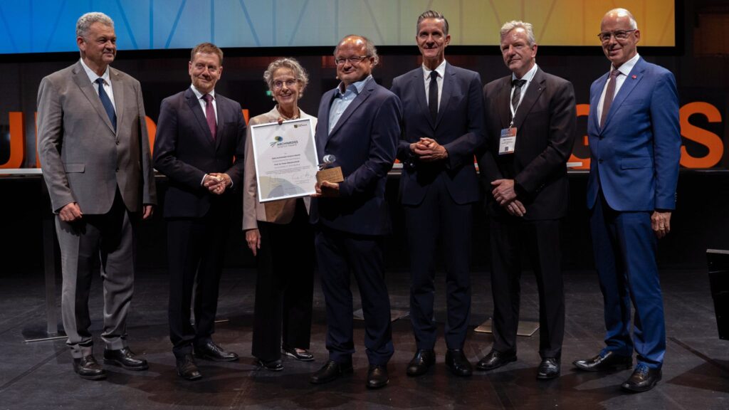 Seven people are standing side by side, smiling at the camera.